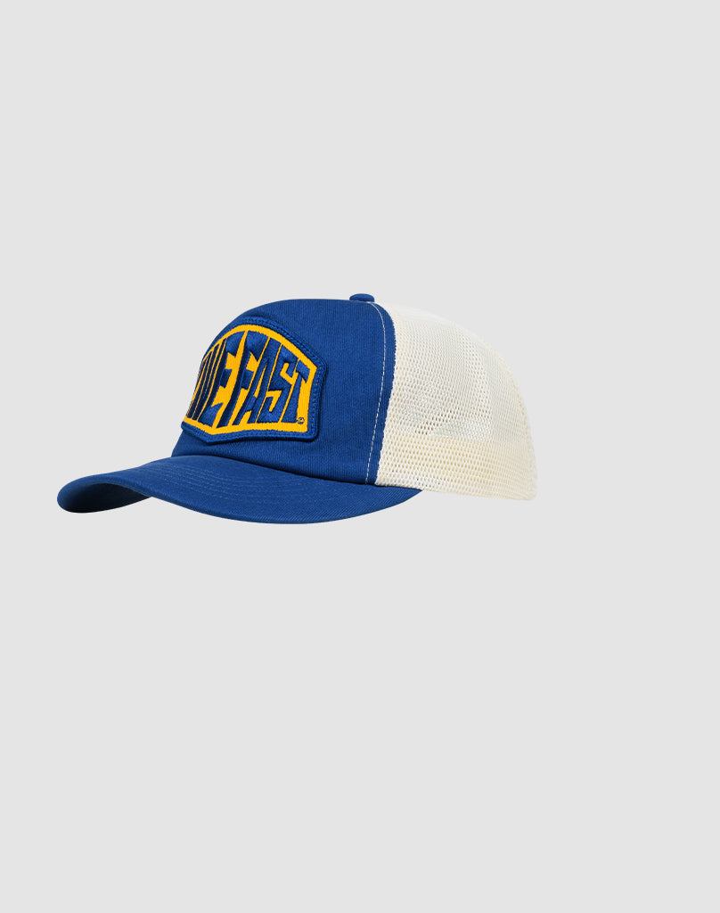 The LFDY Patched Trucker by LIVE FAST DIE YOUNG is a blue and white trucker cap with a curved brim, mesh panels, snap closure, and a yellow front patch featuring bold blue DIE FAST text.