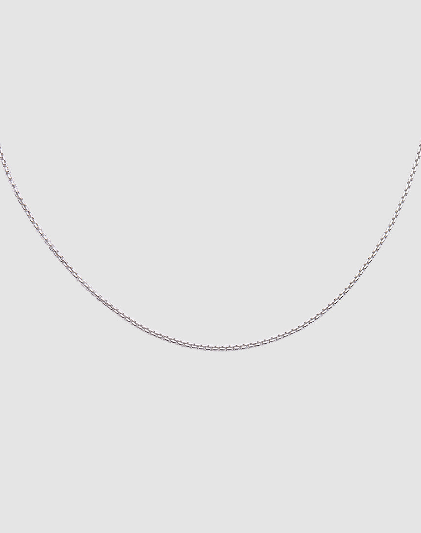 The LIVE FAST DIE YOUNG Thin Curb Chain, crafted from 925 Sterling Silver, is shown against a plain light gray background with only the lower half of the chain visible in a gentle curve.