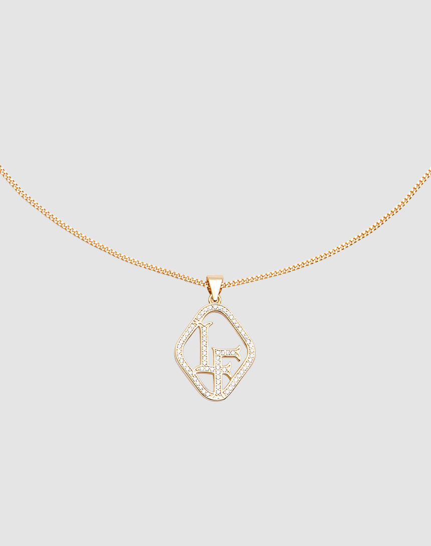 The LF Chain by LIVE FAST DIE YOUNG is a delicate gold necklace with a Zirkonia Anhänger displaying the initials LF in sparkling crystals, set against a light gray background.