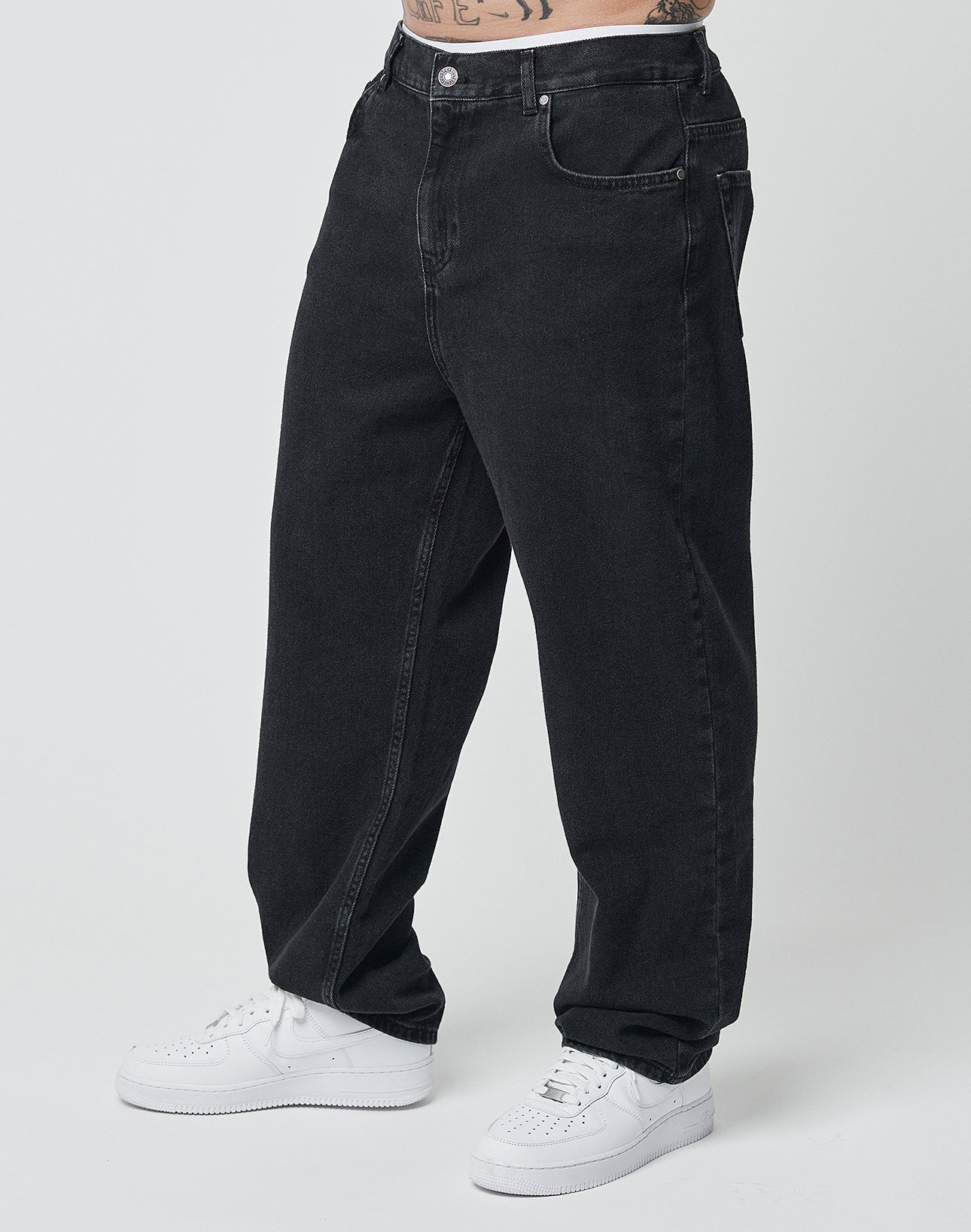 Eine Person trägt die Wide Denim von LIVE FAST DIE YOUNG in Schwarz. Zu sehen sind nur Unterkörper und Beine vor einem schlichten, hellen Hintergrund.