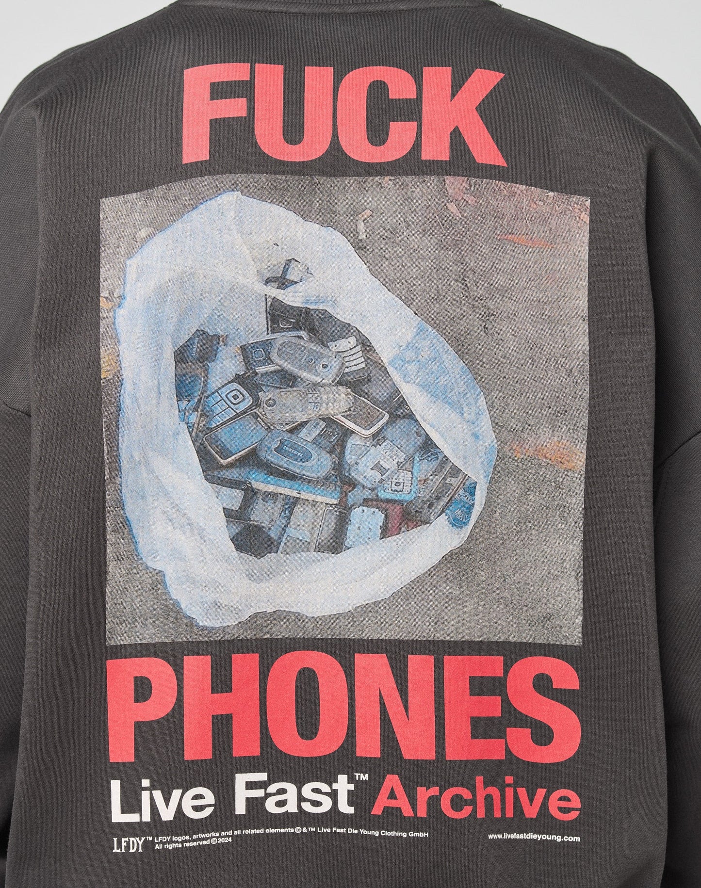 The LFDY F*ck Sweater by LIVE FAST DIE YOUNG features an oversized fit, bold red F*CK PHONES text above a photo of a plastic bag with old phones, and “Live Fast Archive” in white and red below. Made from a soft Baumwolle blend.