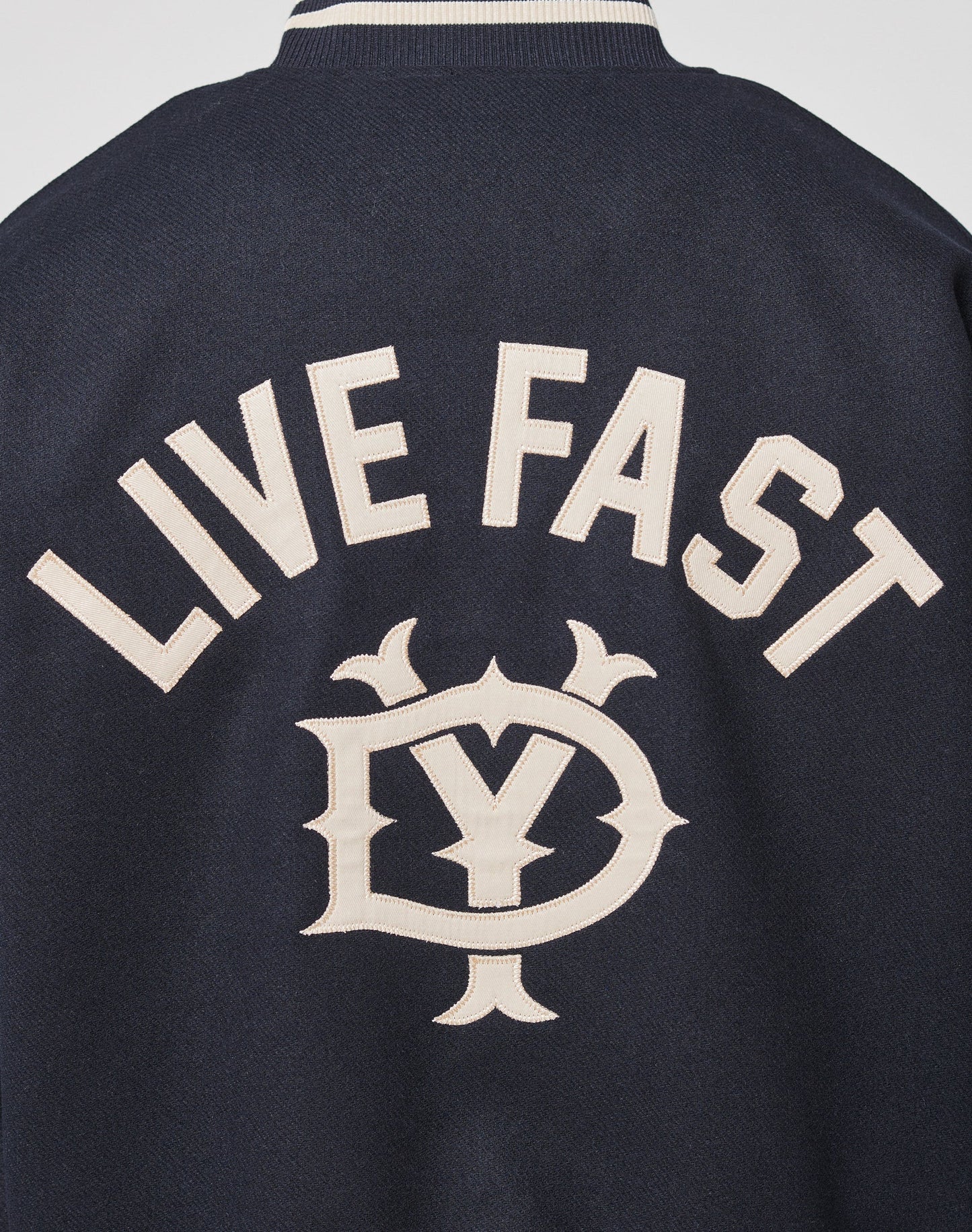 The Live Fast College Jacket by LIVE FAST DIE YOUNG is a navy blue Regular Fit jacket with LIVE FAST boldly in white on the back, above a stylish Y and D emblem, and features Rückenstick Gefüttert for extra comfort and style.