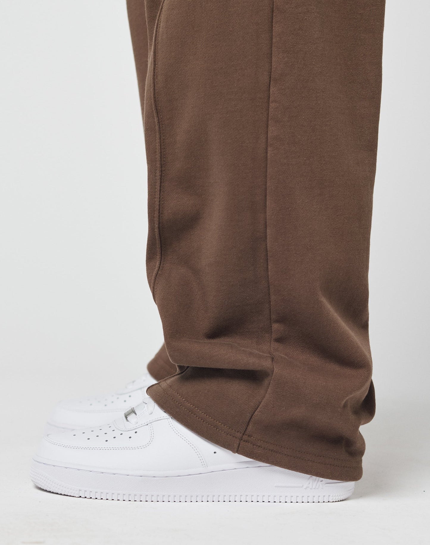 A person models the LIVE FAST DIE YOUNG Basic Wide Jogger with seitliche Eingrifftaschen, draped over white sneakers, against a plain white background.