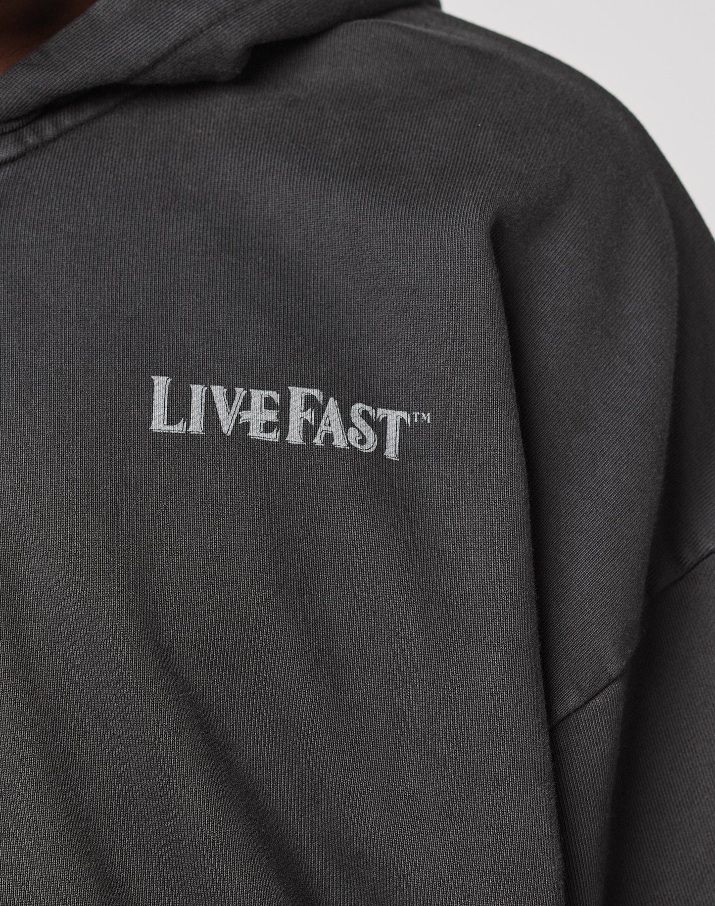 Close-up of the LFDY Loyal Hooded Zip by LIVE FAST DIE YOUNG, a dark hoodie with Vintage Waschung and LIVE FAST™ in white on the chest, made from 100% Baumwolle in an Oversize Fit.