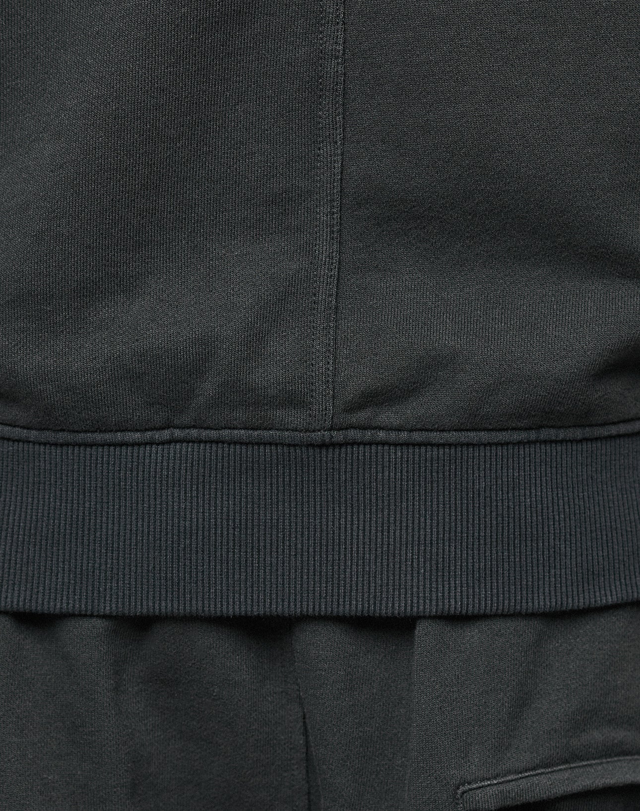 Close-up of the bottom hem and ribbed waistband of the LIVE FAST DIE YOUNG LFDY Lightweight Hooded Zip, showing stitching details with matching black Regular Fit pants below. Made from 100% Baumwolle for comfort.