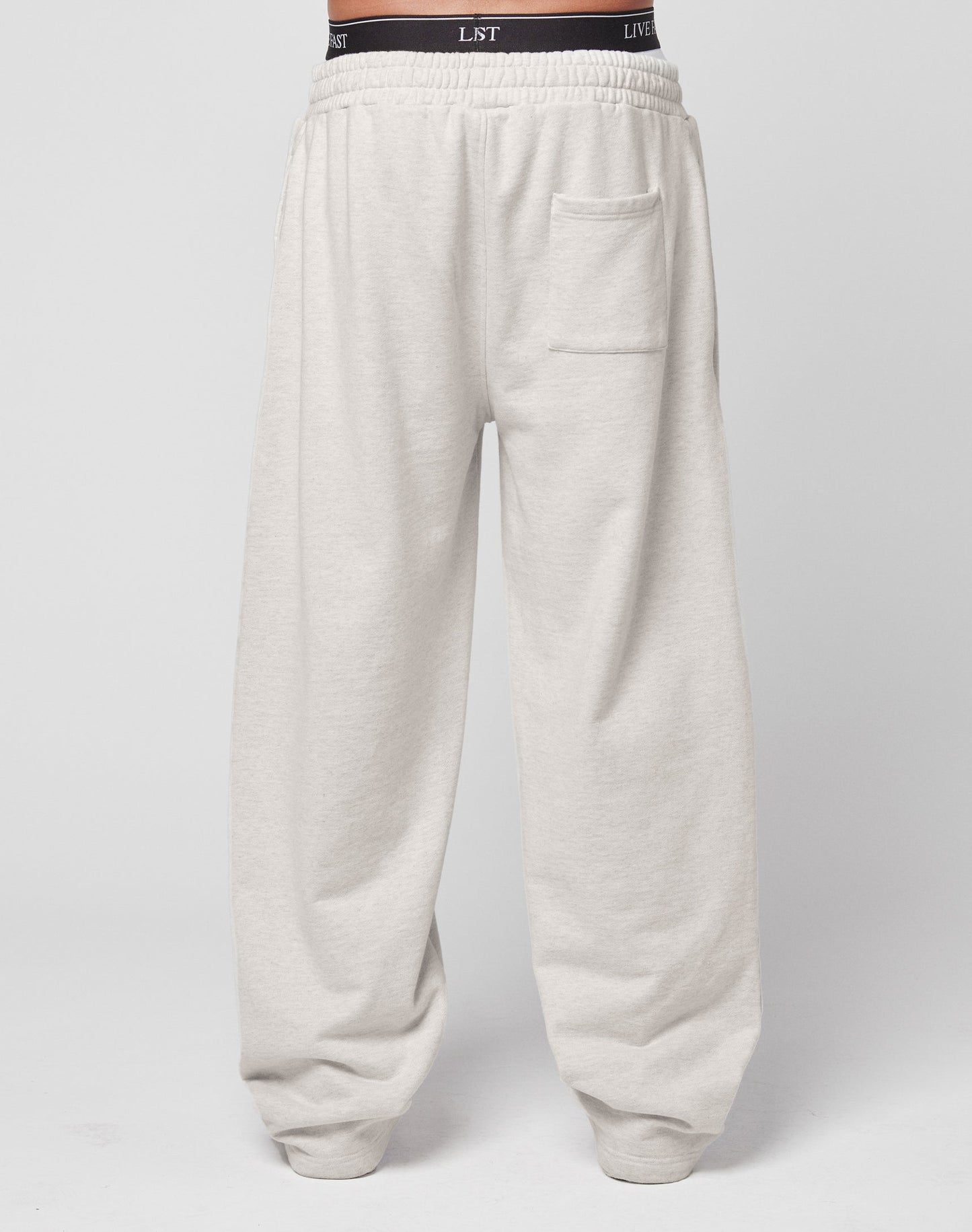 Die DY Jogger von LIVE FAST DIE YOUNG sind beige Sweatpants mit weitem Bein, Oversize Fit, elastischem Bund mit sichtbarem Text, rechter Gesäßtasche und entspannter Passform aus 100% Baumwolle.