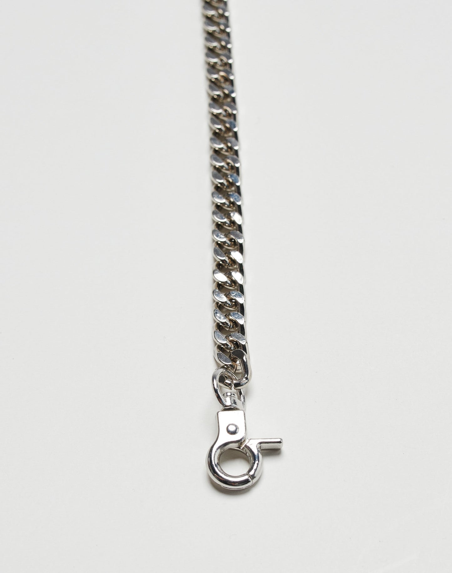 A close-up of a silver chain necklace with a lobster clasp on white, next to the sleek Live Fast Wallet by LIVE FAST DIE YOUNG, featuring subtle brand detailing.
