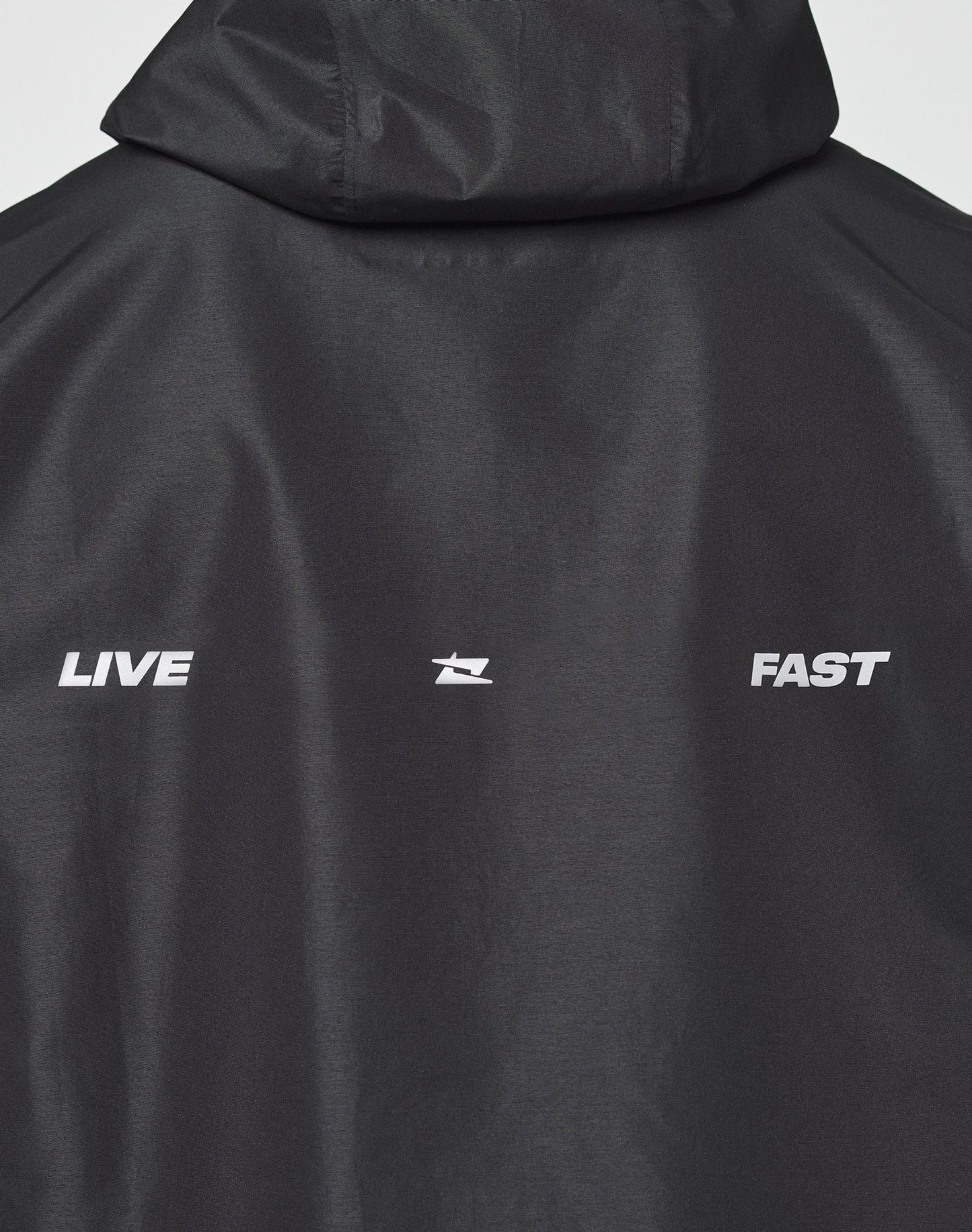 The LIVE FAST DIE YOUNG Live Fast Performance Rain Jacket is black with LIVE and FAST in white on the back, split by a small white logo. It features a regular fit and elastic cuffs for comfort.