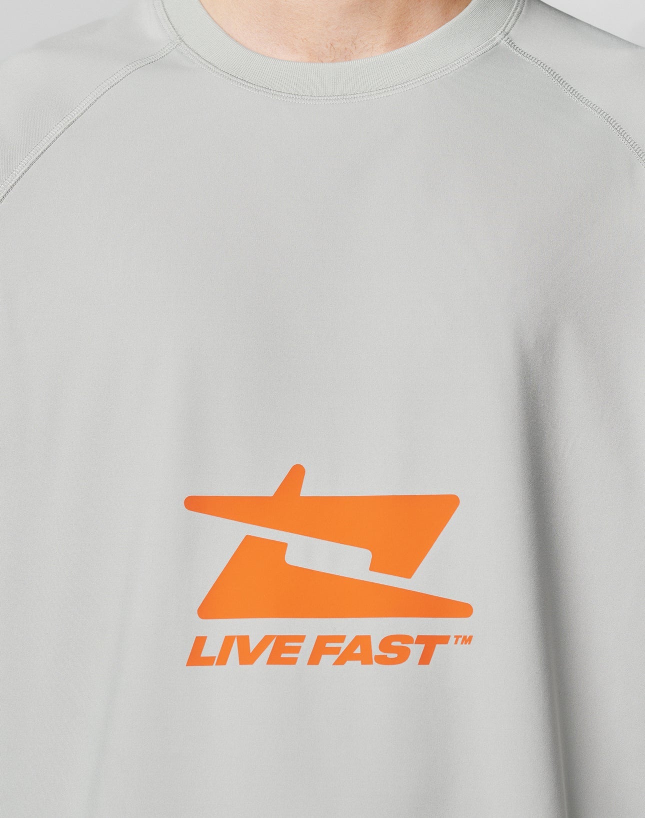 The LFDY Sports Longsleeve by LIVE FAST DIE YOUNG features a light gray color, an abstract orange graphic, and bold LIVE FAST™ text on the chest, all in an oversize fit for a relaxed, modern style.