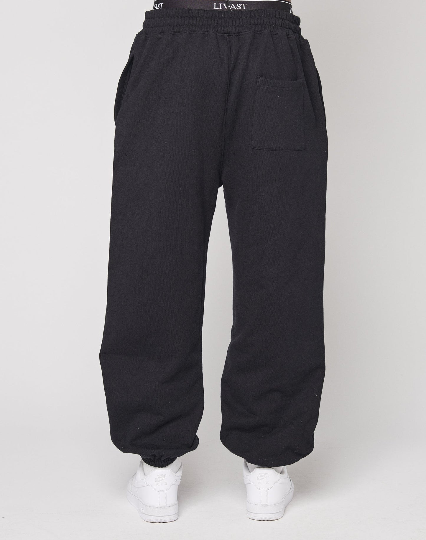 Model showcases the DY Loose Jogger by LIVE FAST DIE YOUNG, featuring a relaxed fit, elastic waistband, and back pocket, paired with white sneakers. Only the lower body is visible against a plain white background.