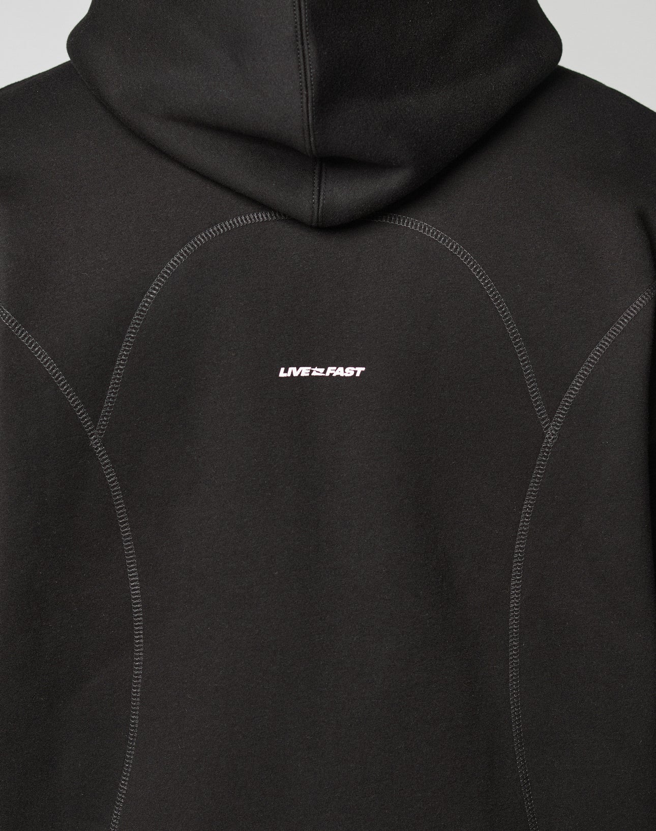 A close-up of the back of the black LFDY Active Fleece Hooded Zip by LIVE FAST DIE YOUNG, featuring an oversize fit, soft cotton fabric, visible stitched seams, and LIVE FAST in small white letters at the center.