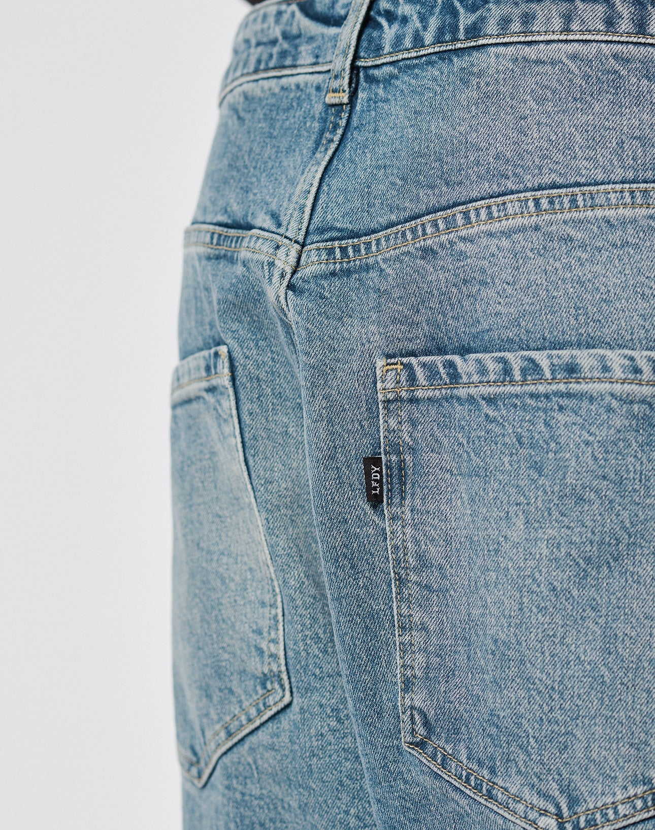 Close-up of the back of LIVE FAST DIE YOUNGs LFDY Tire Tracks Denim in a Baggy Fit, featuring two back pockets and a black label on the right pocket seam. Made from 100% Baumwolle for comfort and durability.
