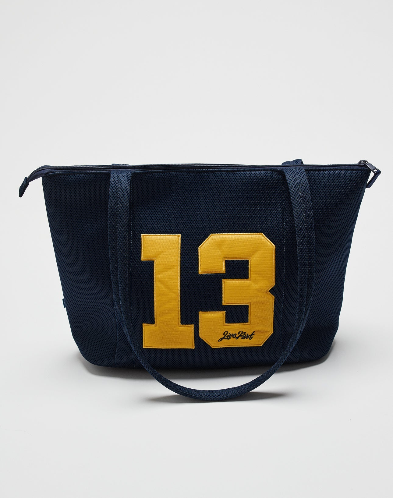 The LFDY Mesh Beach Bag by LIVE FAST DIE YOUNG is a navy tote with two handles, a large yellow 13 on the front, and a practical zipper. The photo shows the bag against a plain white background.