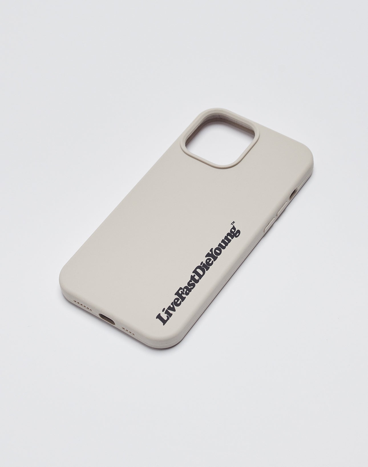 A beige Basic Phone Case by LIVE FAST DIE YOUNG rests on a white surface, featuring the bold LiveFastDieYoung logo near the bottom right for a sleek, statement look.
