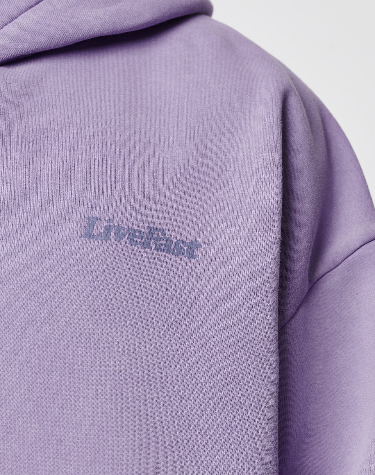Close-up of the Basic 360 Hooded by LIVE FAST DIE YOUNG in lavender Vintage-Waschung. LiveFast is printed in light gray on the chest. The soft Baumwolle-Polyester blend, partial hood, and Oversize Fit ensure comfort.