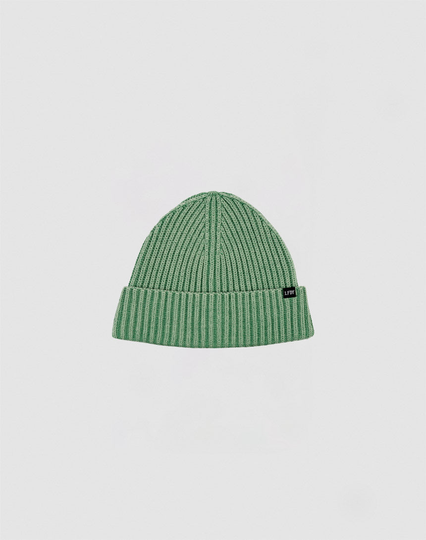 The LIVE FAST DIE YOUNG Washed Rib Knit Beanie in green, made of cotton with a folded cuff and a small black side tag, is shown against a plain white background.