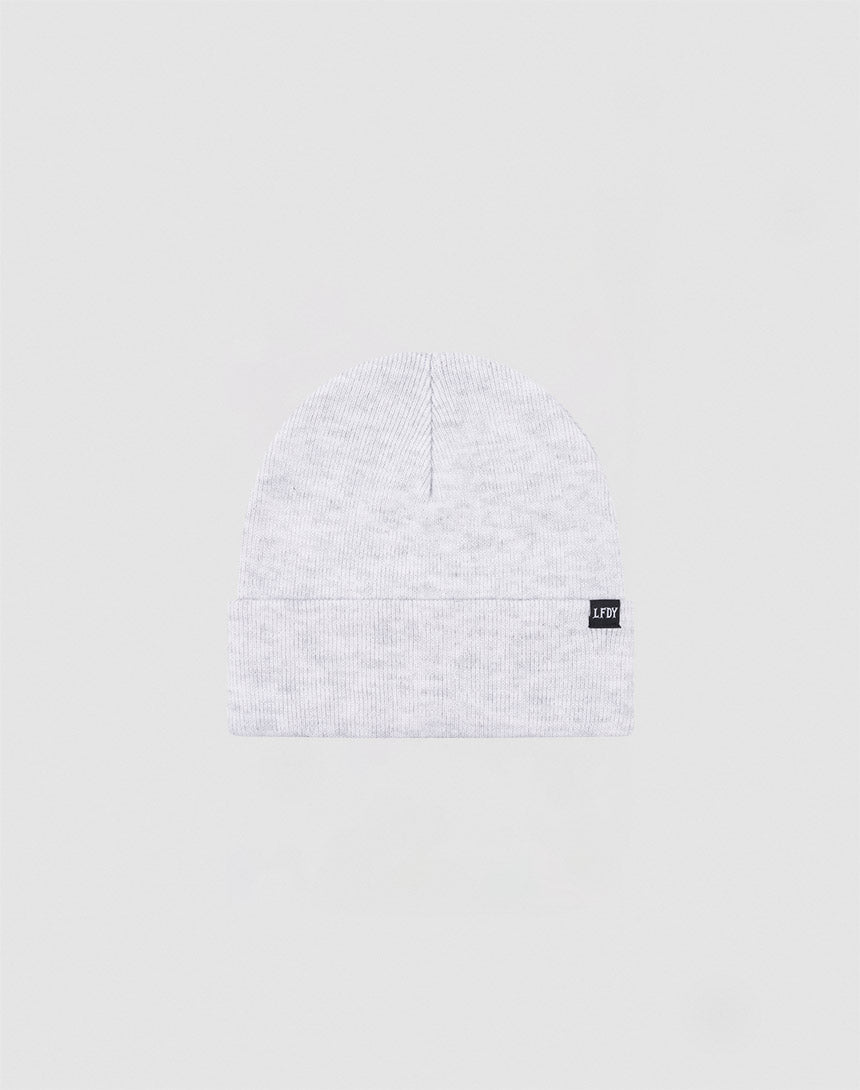 The LIVE FAST DIE YOUNG Basic Beanie is a light gray Polyacryl knit, one size, with a folded cuff and a small black rectangular flaglabel with white text on the cuff, shown against a plain light background.