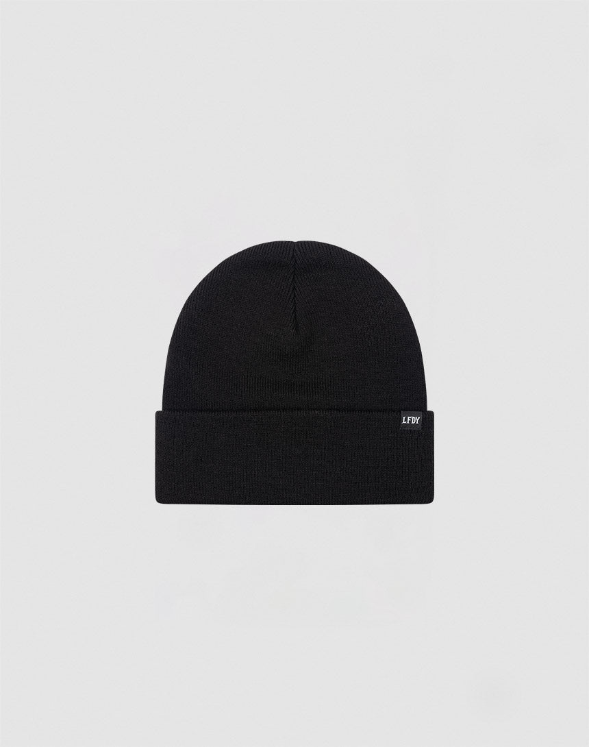 The LIVE FAST DIE YOUNG Basic Beanie is plain black, made from 100% cotton, features a folded brim and a small rectangular side tag. Presented on a light gray background. Care: Gentle washing recommended.