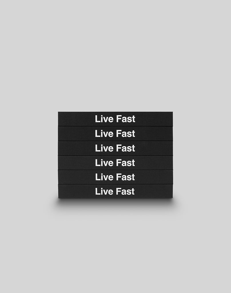 Six black hardcover LFDY Brand Bible books from LIVE FAST DIE YOUNG are stacked horizontally, each boldly displaying Live Fast in white letters against a plain light gray background.