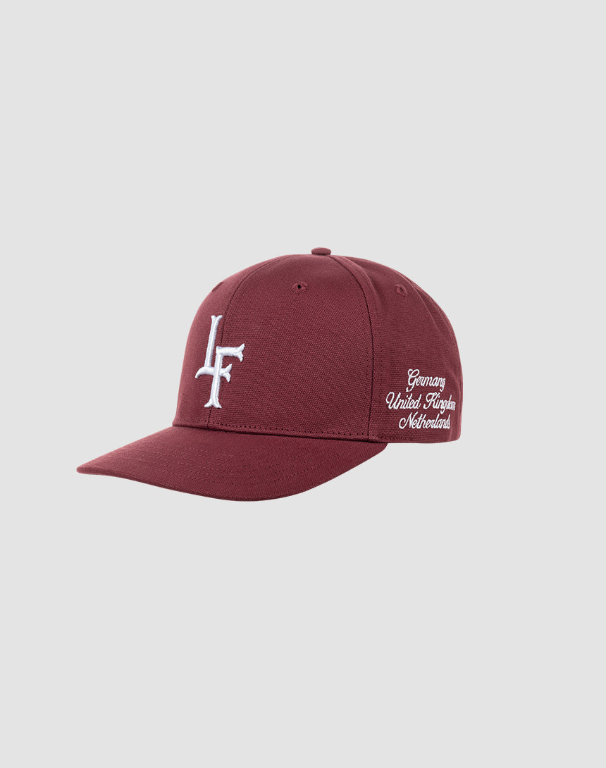 The LF Snapback by LIVE FAST DIE YOUNG is a maroon Baumwolle baseball cap featuring a white LF Logo-Stick front, embroidered Germany, United Kingdom, Netherlands text on the side, and a snap closure for adjustable fit. Shown on a plain light background.