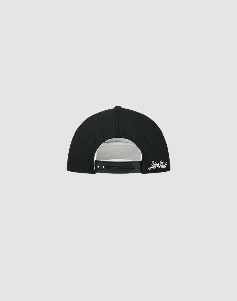 The LFDY X NEW ERA Monaco Boys by LIVE FAST DIE YOUNG is a black 9Fifty A-Frame snapback, shown from the back with an adjustable strap and white script above it. Its low-profile silhouette stands out against a plain light gray background.