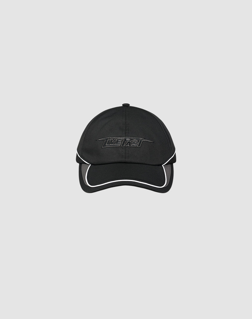 The LIVE FAST DIE YOUNG Live Fast 3000 Cap is a black polyester baseball cap with white trim, an embroidered Logo-Stick on the front, and a Klettverschluss at the back, shown against a light gray background.