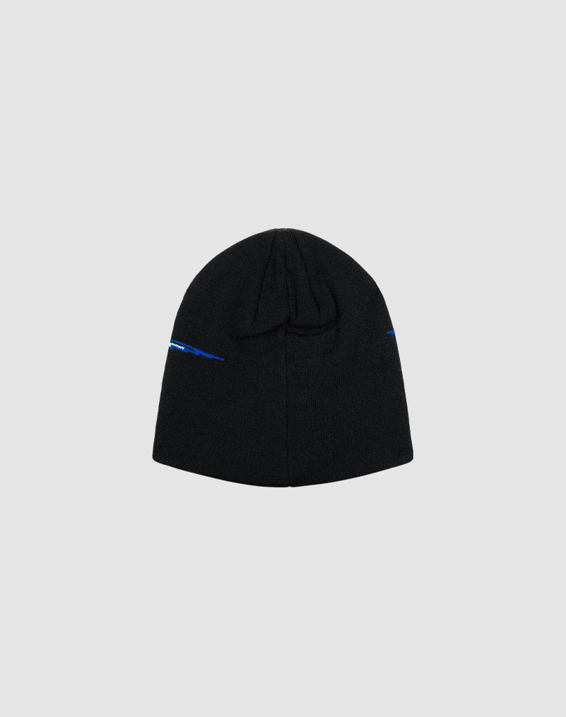 The LIVE FAST DIE YOUNG Live Fast 3000 Beanie is a black knit hat made from soft Polyacryl, with a small blue Logo-Strick detail near the edge, shown flat on a light gray background.