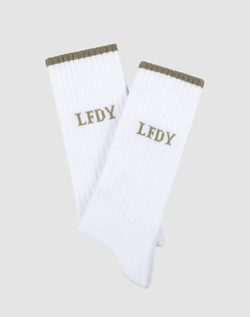 The Basic Stripe Socks (2 Pack) by LIVE FAST DIE YOUNG are white ribbed socks with olive green tops and LFDY embroidery, made from a soft cotton blend with elastane and polyamide, shown on a light gray background.