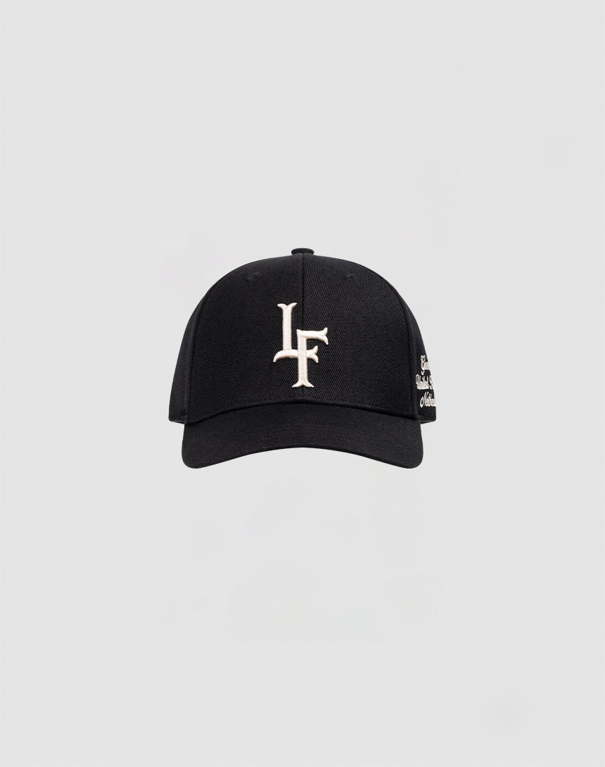 The LF Snapback by LIVE FAST DIE YOUNG is a black cotton baseball cap with white LF logo embroidery on the front and a snap closure, shown against a plain light gray background.