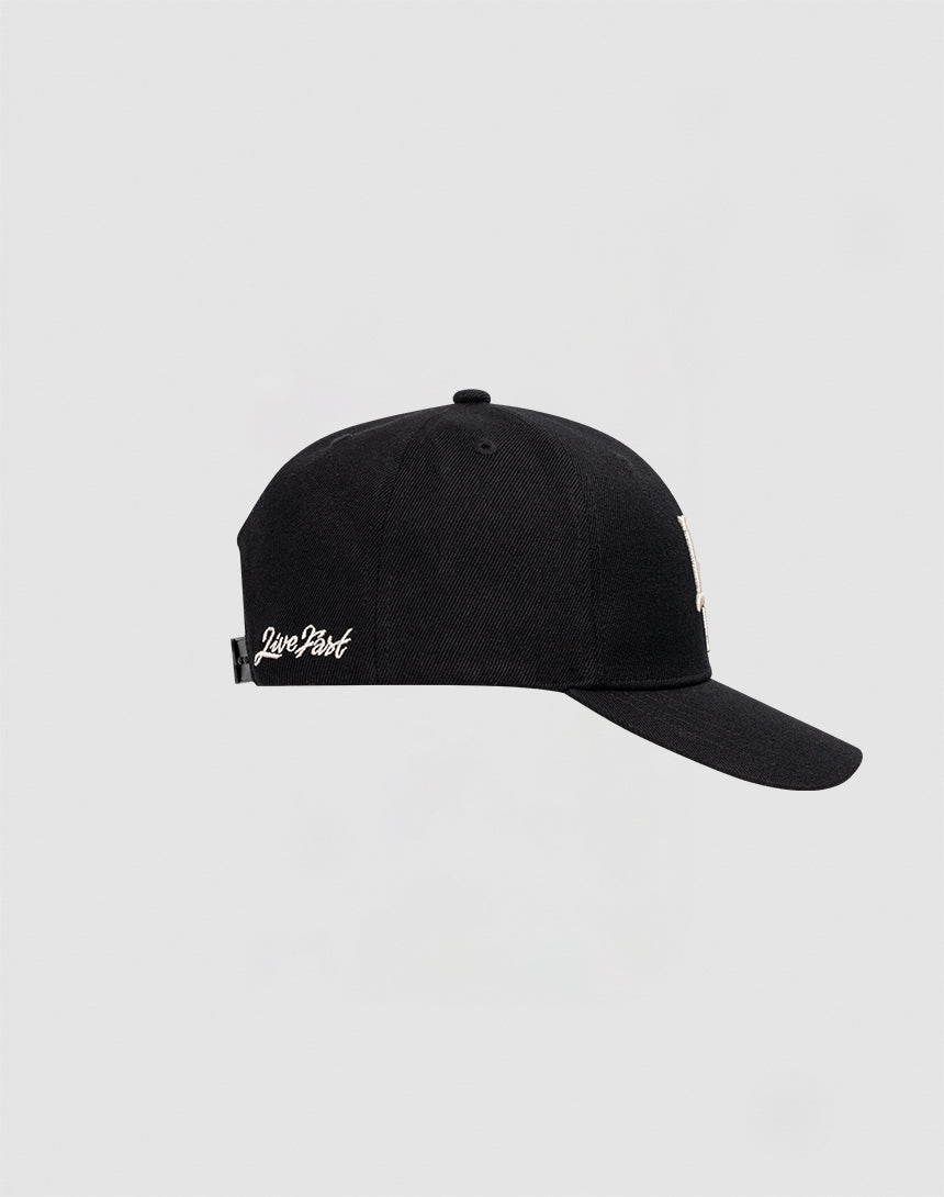 Die LF Snapback von LIVE FAST DIE YOUNG: Schwarze Baumwoll-Cap mit Snapverschluss, seitlich gezeigt. Der weiße Live Fast-Logo-Stick schmückt die Rückseite auf schlichtem hellgrauem Hintergrund.