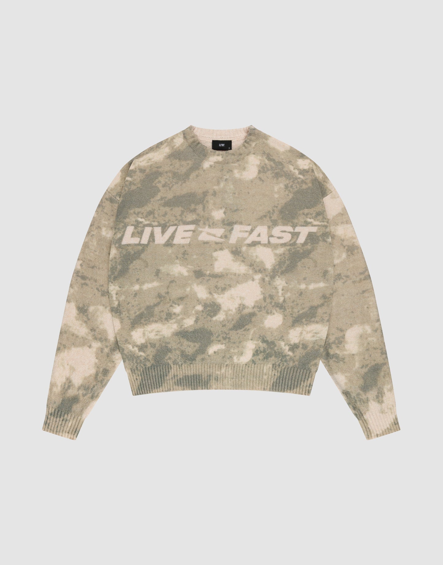 The Live Fast Boucle Sweater by LIVE FAST DIE YOUNG features a beige and green camo pattern, an oversized fit, and bold white "LIVE FAST" lettering across the chest, displayed on a plain light background.
