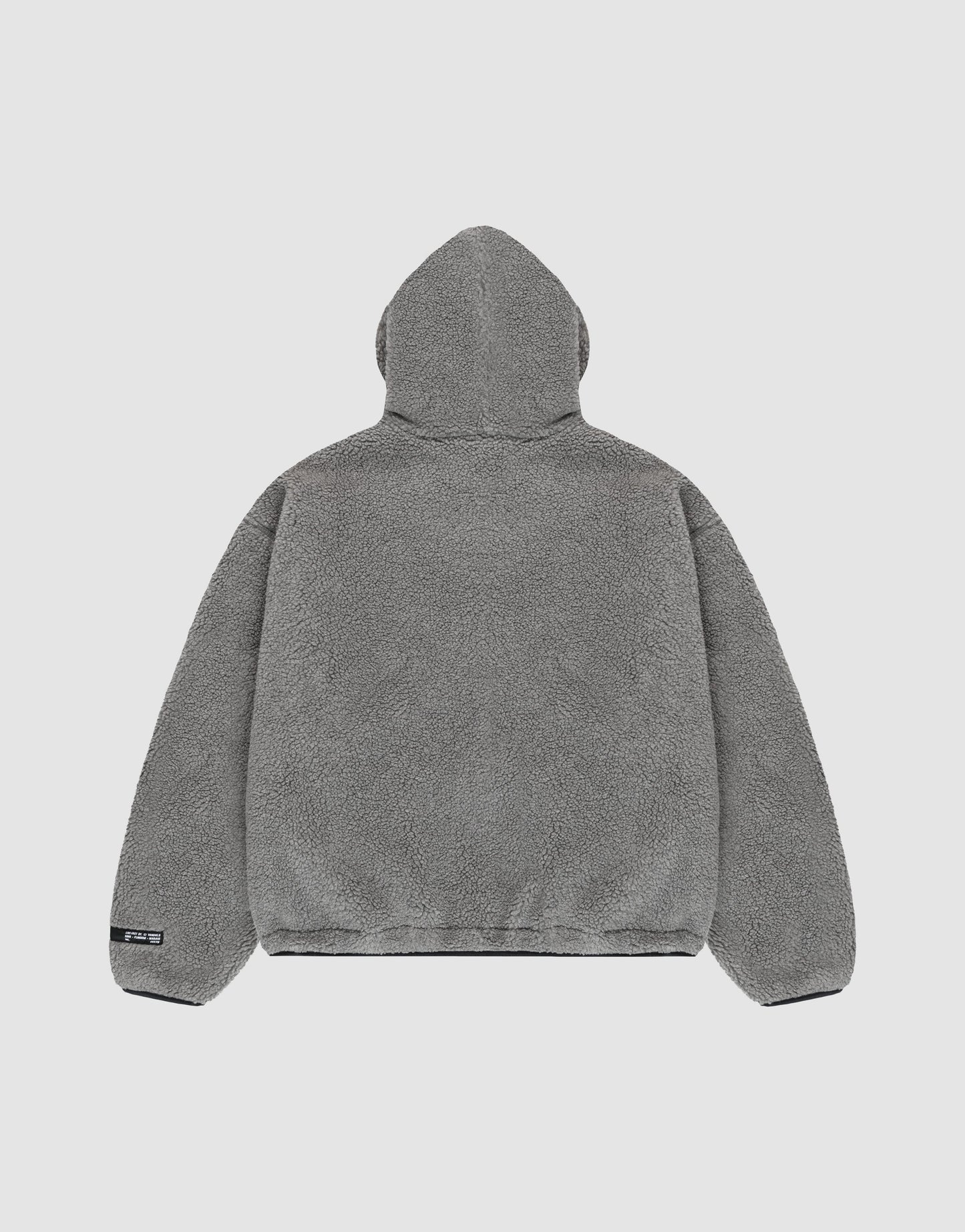 The LIVE FAST DIE YOUNG LFDY Teddy Hooded jacket in gray fleece is shown from the back on a plain light background. It features a soft, plush texture, oversize fit, long sleeves, and a small black tag on the lower left hem.