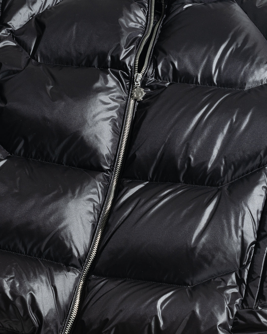 Close-up of a shiny black Live Fast Down Jacket by LIVE FAST DIE YOUNG, with horizontal quilting, a silver center zipper, wasserabweisend fabric, glossy finish, and 600er Fillpower for warmth.