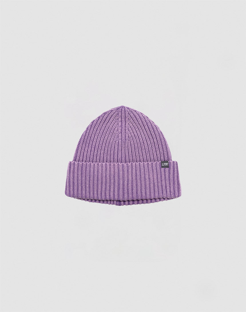The Washed Rib Knit Beanie by LIVE FAST DIE YOUNG is a pastel purple, ribbed hat with a folded brim, soft cotton fabric, and a small black LTP tag on the side, shown against a plain white background.