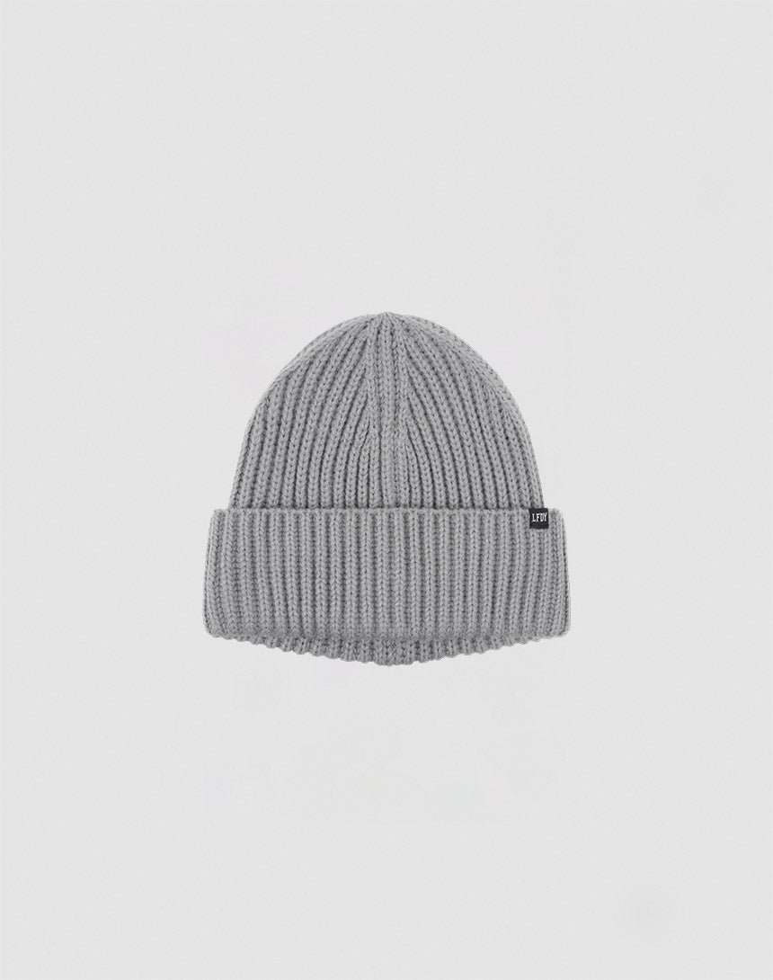 A gray LIVE FAST DIE YOUNG Rib Knit Beanie in One Size, featuring a folded brim and a small black flag label on the side, displayed against a plain white background.