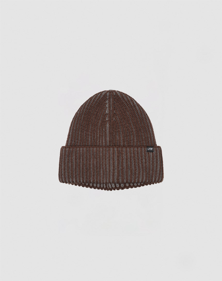 The LIVE FAST DIE YOUNG 2 Tone Rib Knit Beanie in brown Polyacryl has a folded brim and a small black flag label with white text, shown against a plain light grey background.
