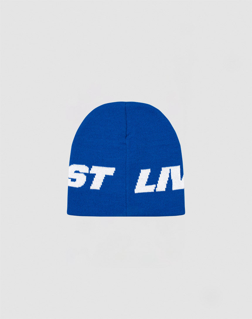 A blue polyacryl Live Fast Jacquard Beanie by LIVE FAST DIE YOUNG features bold white, partially visible Logo Strick text wrapping around it, displayed on a plain light gray background. Model: LF2410-16488.