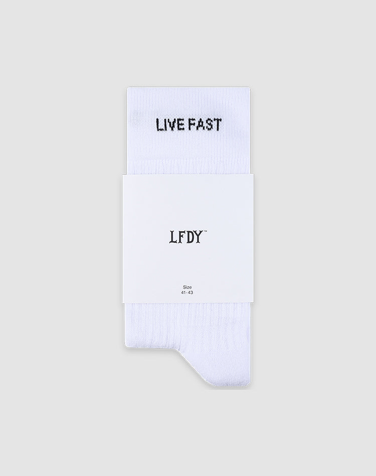 A pair of white LFDY Performance Socks by LIVE FAST DIE YOUNG featuring "LIVE FAST" in black on the cuff, with a white label showing LFDY, LF2601-19869, and size. Made from soft Baumwolle and set against a light grey background.