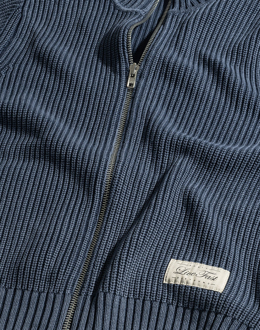A close-up of the LFDY Knit Jacket by LIVE FAST DIE YOUNG shows a blue ribbed zip-up sweater with a Stehkragen, metal zipper, and a sewn-on white label reading "Inter Tradi Classic.