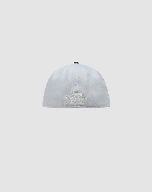 A light gray LFDY X NEW ERA 59FIFTY fitted cap by LIVE FAST DIE YOUNG, shown from the back with gold embroidery of Germany, United Kingdom, and Switzerland on a plain background. Größentabelle available for perfect sizing.