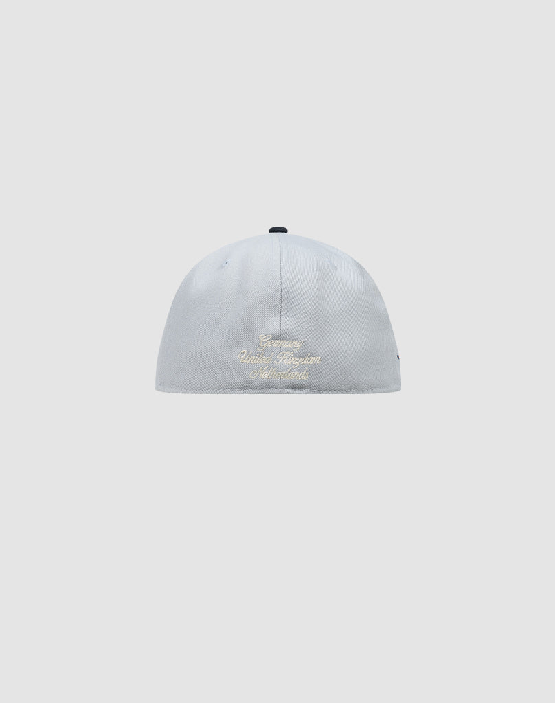 A light gray LFDY X NEW ERA 59FIFTY fitted cap by LIVE FAST DIE YOUNG, shown from the back with gold embroidery of Germany, United Kingdom, and Switzerland on a plain background. Größentabelle available for perfect sizing.