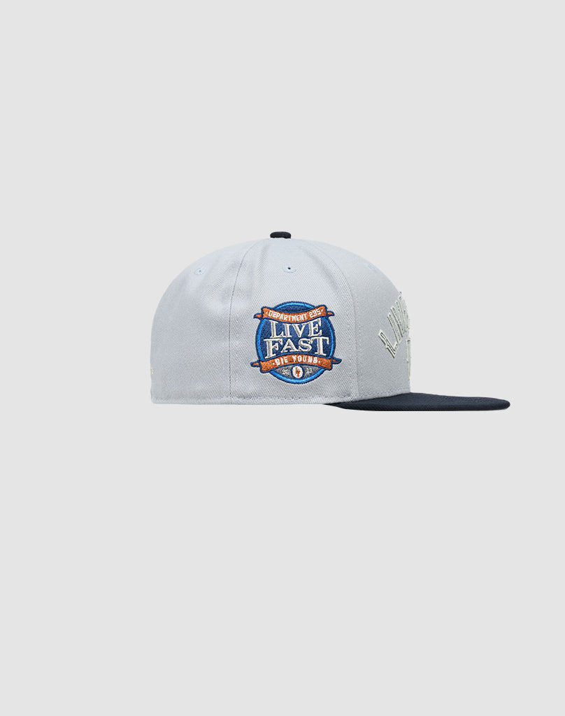 The LFDY X NEW ERA 59FIFTY by LIVE FAST DIE YOUNG is a light gray fitted cap with a navy blue flat brim and a colorful “Live Fast” patch on the side. Größentabelle available for perfect fit.