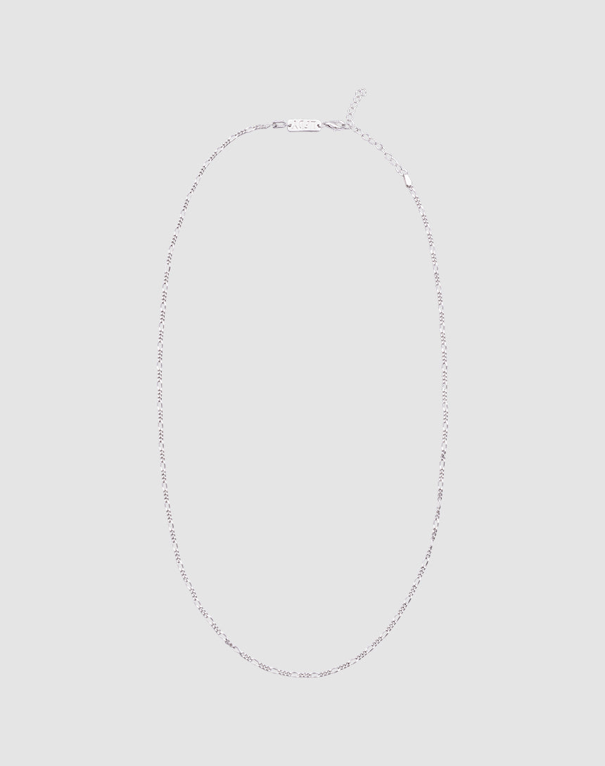 The LIVE FAST DIE YOUNG Basic Figaro Chain is a delicate 925 Sterling Silber necklace with a simple clasp, shown in an oval on a light gray background. Die Kettenlänge ist verstellbar für deine perfekte Passform.| plain