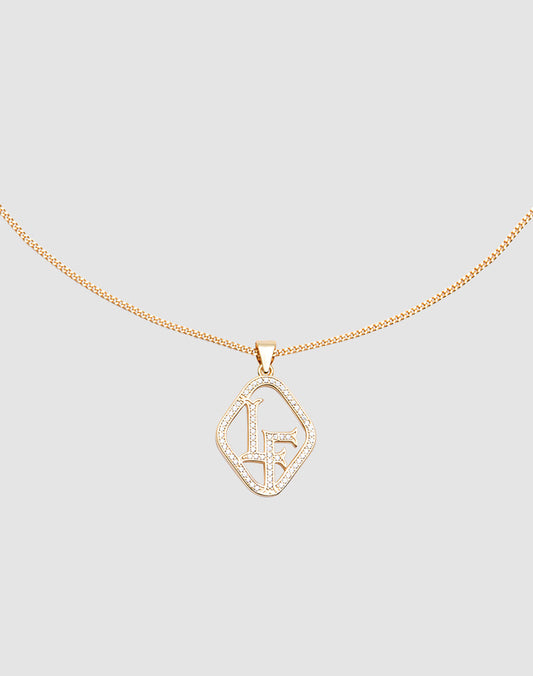 The LF Chain by LIVE FAST DIE YOUNG is a delicate gold necklace with a Zirkonia Anhänger displaying the initials LF in sparkling crystals, set against a light gray background.