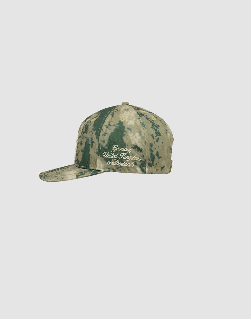 The LF Snapback by LIVE FAST DIE YOUNG is a green and tan camo baseball cap made from 100% Baumwolle, featuring the Genius United Kingdom Worldwide logo embroidered in white on the front.