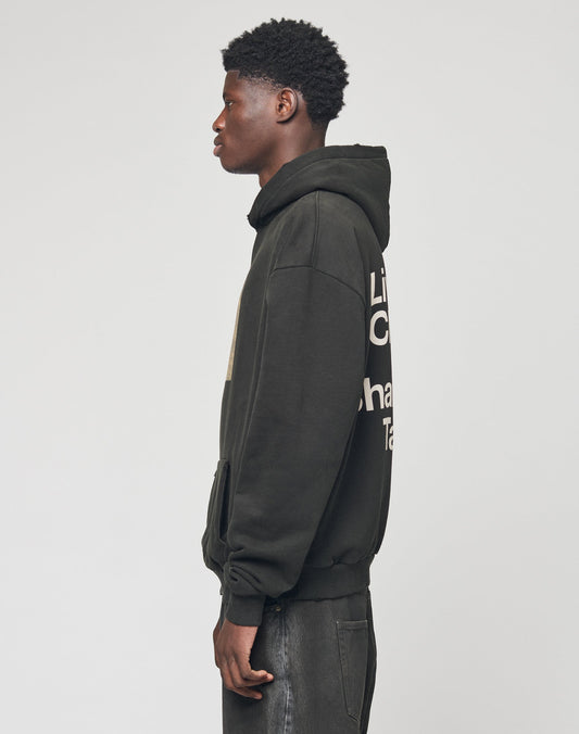 A young man in profile wears the black LFDY Sharkhunter Hooded by LIVE FAST DIE YOUNG with white back text and dark jeans, set against a plain light background.