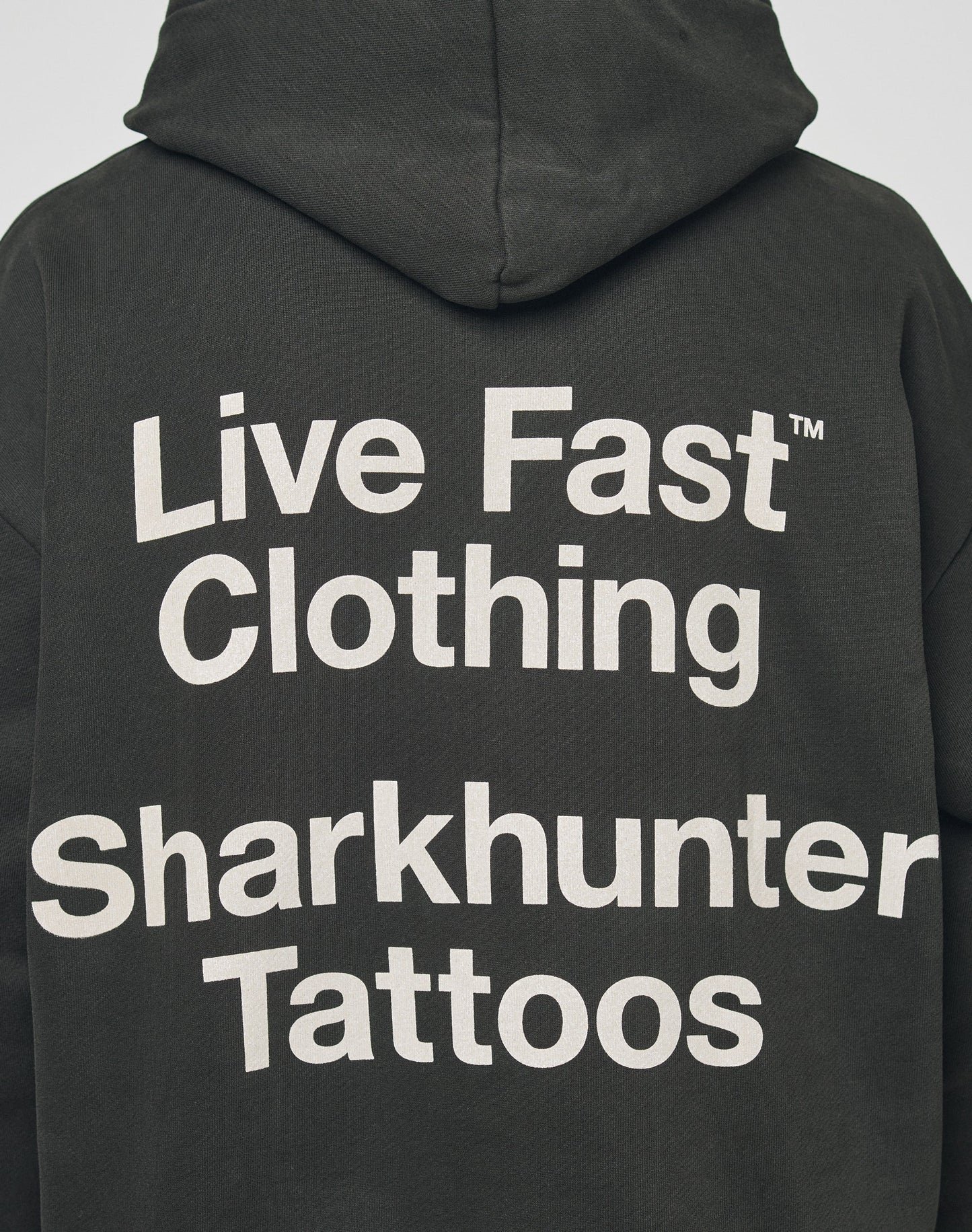 The LFDY Sharkhunter Hooded by LIVE FAST DIE YOUNG is an oversized black hoodie crafted from soft cotton, featuring bold white Live Fast Clothing Sharkhunter Tattoos text printed on the back.