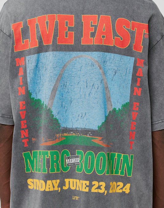 The LFDY Metro Boomin Tee by LIVE FAST DIE YOUNG is a gray 100% Baumwolle shirt featuring the Gateway Arch graphic, bold red and yellow event text, an Ärmelprint detail, and a parental advisory label.