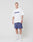 A person stands against a white background, wearing the LIVE FAST DIE YOUNG Basic Tee (LF2404-15446, 100% Baumwolle) with LiveFast in blue, paired with blue basketball shorts, white crew socks, and white sneakers.