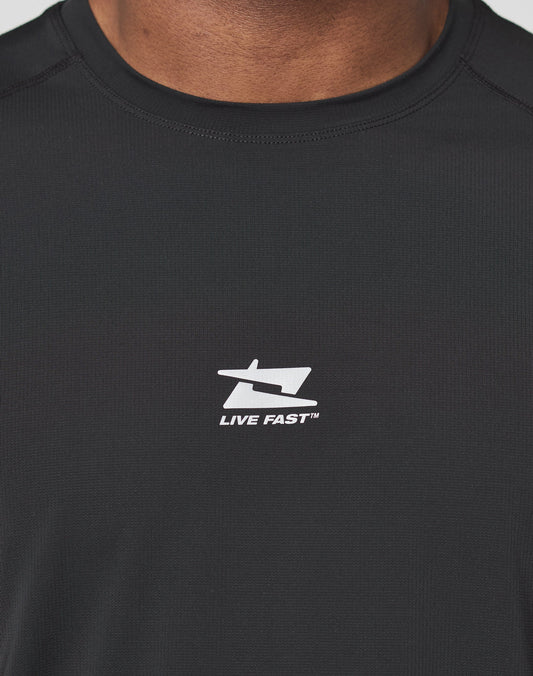 Close-up of a person wearing the LIVE FAST DIE YOUNG Live Fast Performance Tee, a black slim-fit shirt made from comfortable nylon spandex, featuring a white stylized “L” and “F” logo above the text “LIVE FAST™” on the chest.